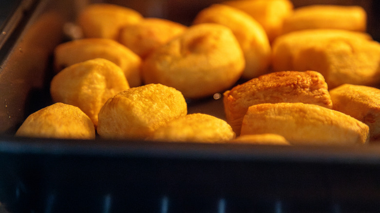 Potato pieces roasting in the oven on a black tray