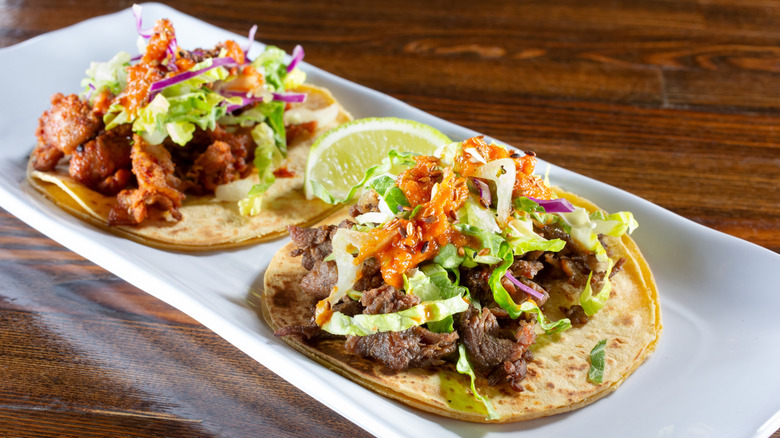 Korean kimchi tacos on a white plate on a wooden table