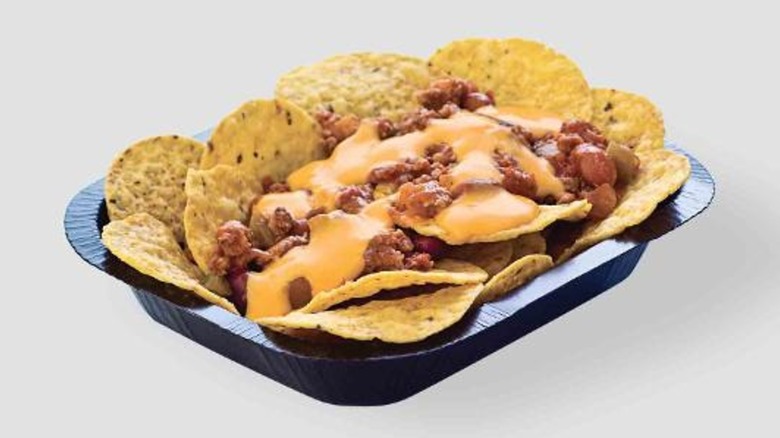 Wendys chili cheese nachos in a back container against a beige background