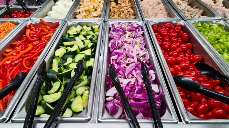 Salad bar compartments with vegetables in metal containers