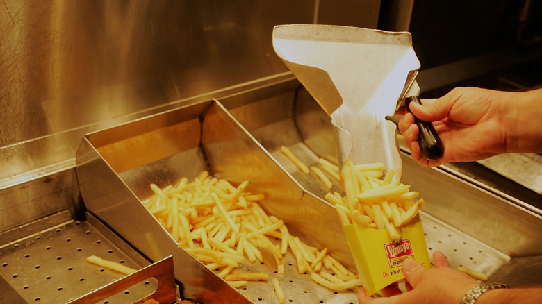Wendy's employee scoops fries into a yellow container