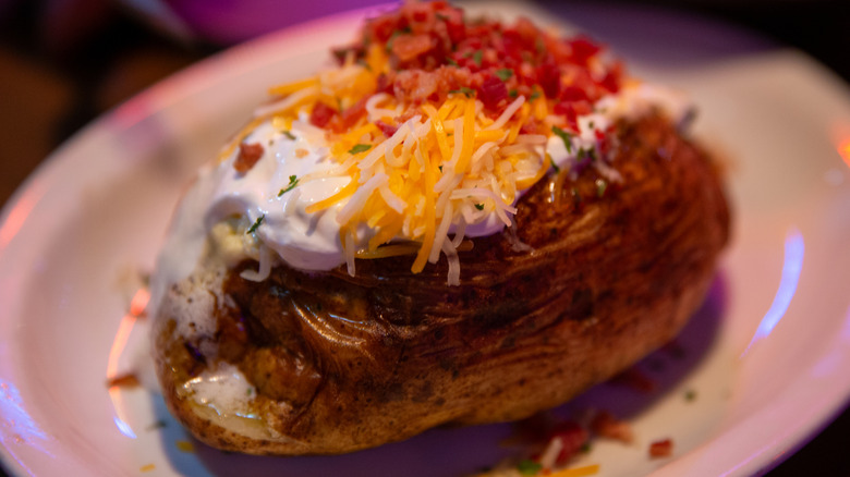Loaded baked potato with sour cream and cheese on a white plate