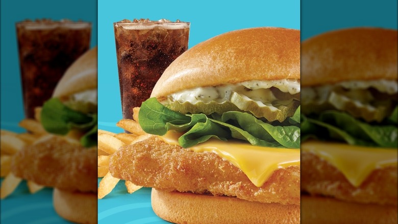 Wendy's fish sandwich with a soda and fries in the background