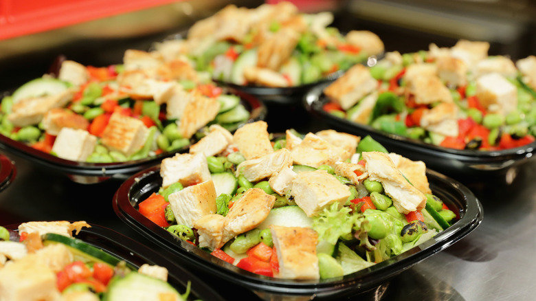 Wendy's salads in black containers on a metal counter