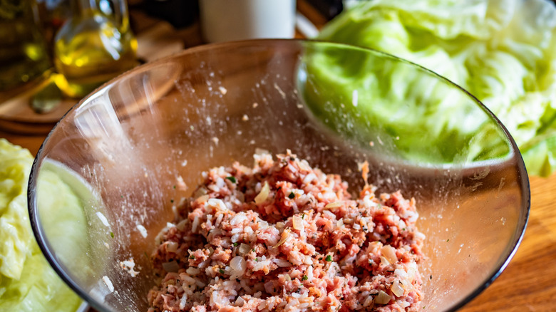 A bowl of spiced, raw ground beef with cabbage in the background