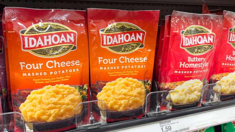 Packages of Idahoan brand Four Cheese Mashed Potatoes and Buttery Homestyle Mashed Potatoes on a store shelf