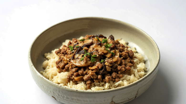 A bowl of rice topped with ground beef and some fresh herbs