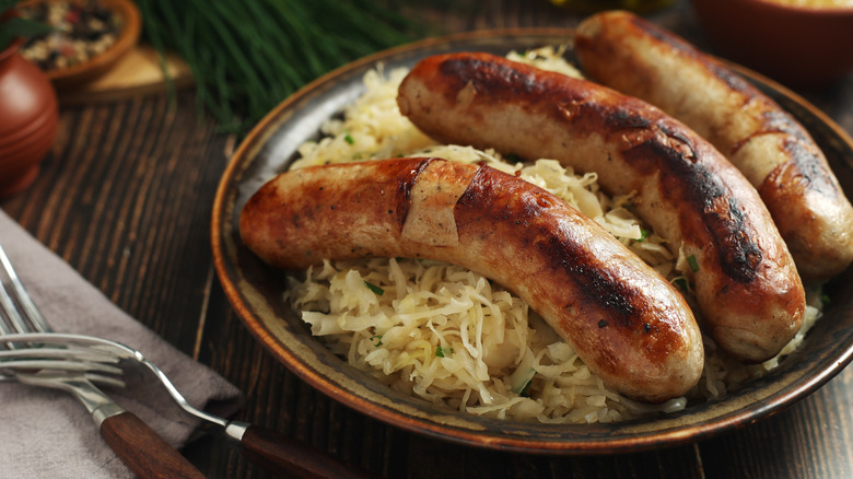 a brown bowl with Bratwurst and sauerkraut