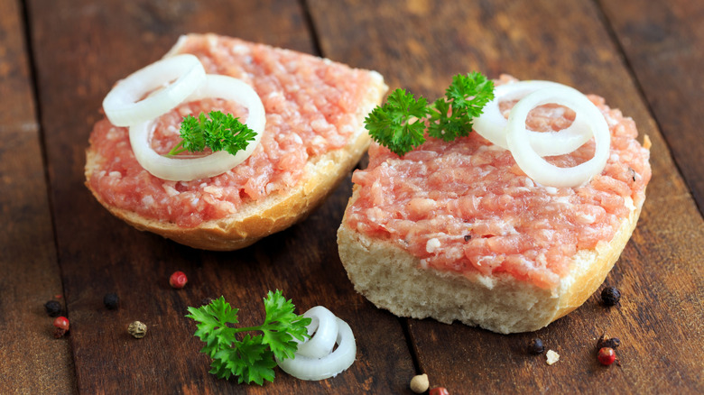 Mettbrötchen with onions on wooden table