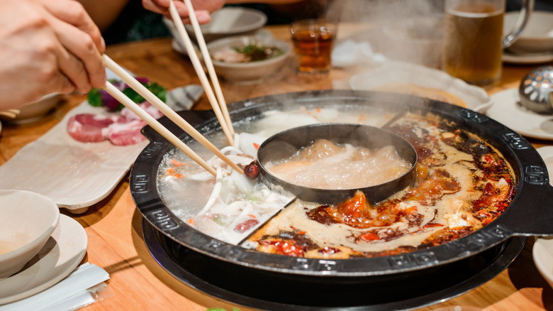 Person eating from a hot pot with chopsticks