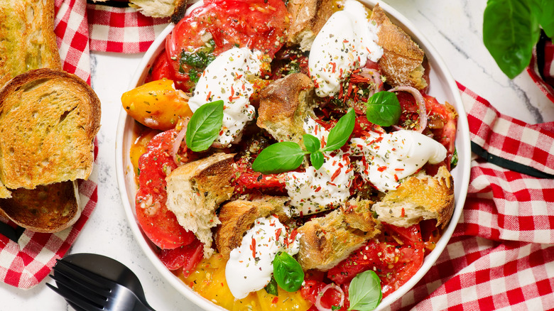 A panzanella salad dish on a red checked table cloth