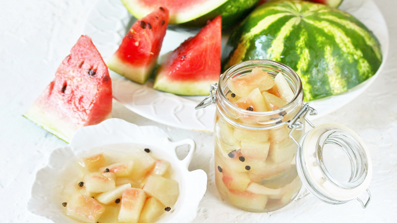 Pickled watermelon rind in jar beside watermelon chunks