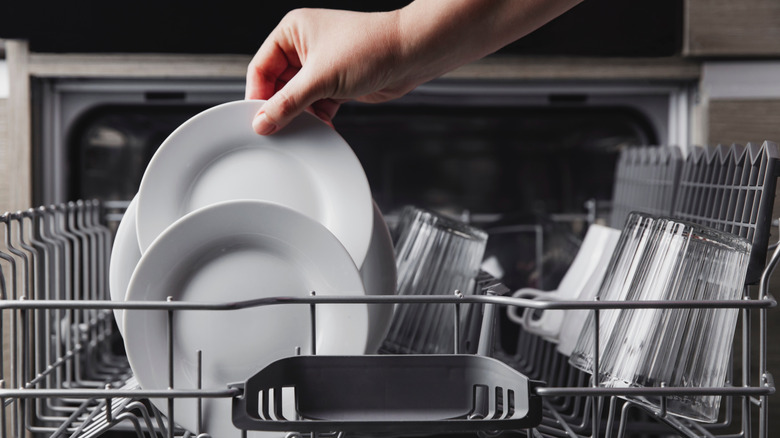 Hand removing dishes from dishwasher