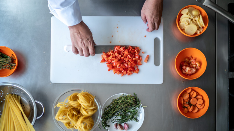 Bird's eye view of bowls of ingredients and person chopping on cutting board
