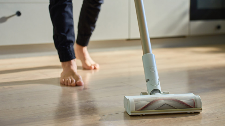 Barefoot person vacuuming floor