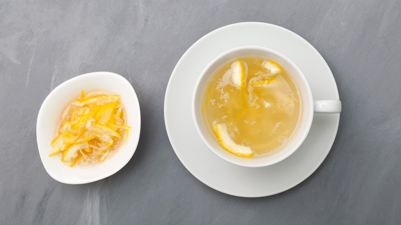 Mug of lemon tea next to bowl of lemon peels