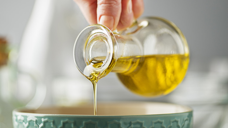Pouring olive oil from jug into bowl