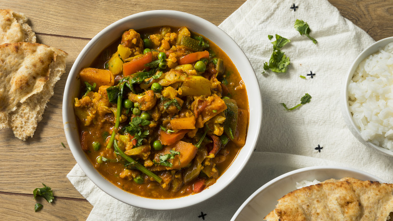 Bowl of vegetable curry with rice and naan bread
