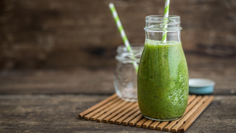 Green smoothie in glass bottle with straw