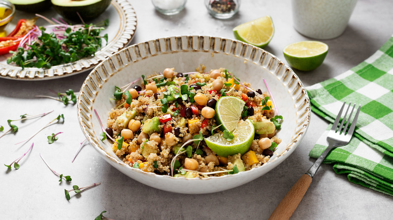 Healthy grains bowl with chickpeas and vegetables, garnished with lime wedges