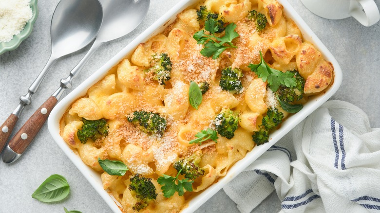 Broccoli mac and cheese in white baking dish, garnished with fresh herbs