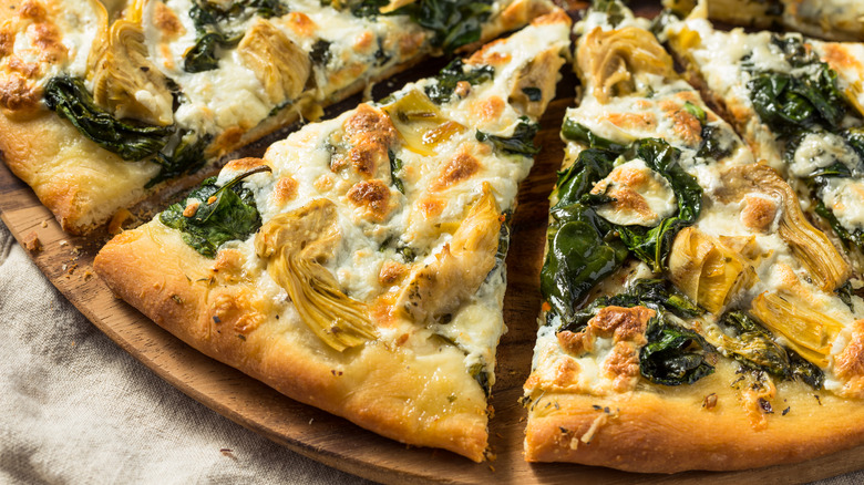 Close up of sliced spinach and artichoke pizza