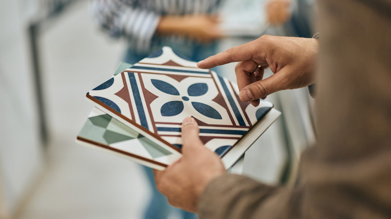 Hand holding samples of patterned tiles