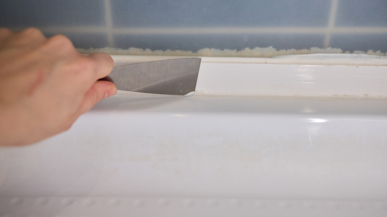 Hand applying caulking with putty knife