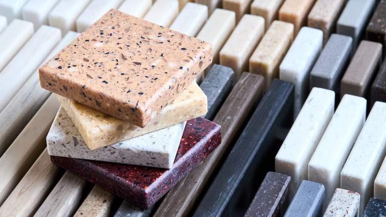 Square samples of kitchen tiles placed above a stack of tiles