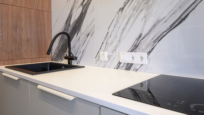 Modern kitchen featuring marble backsplash with electrical outlets
