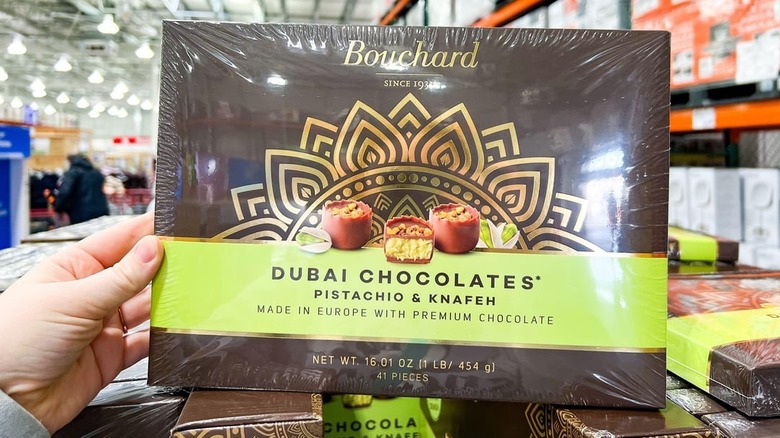 A person holding a box of Bouchard Dubai Chocolates with Pistachio & Knafeh in a Costco warehouse
