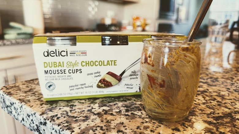 A box of Delici Dubai-Style Chocolate Mousse Cups on a kitchen counter with an empty jar of mousse next to it