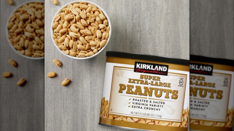 A large can and bowl full of Kirkland Signature Super Extra-Large Peanuts on a light wooden table