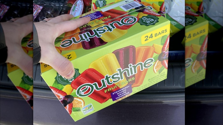 A person holding a box of Outshine Fruit Bars from Costco