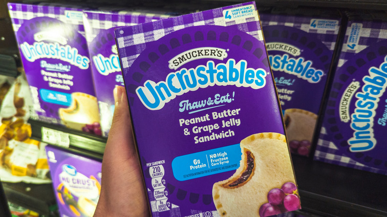 A person holding a package of Smucker's Uncrustables in Peanut Butter & Grape Jelly flavor