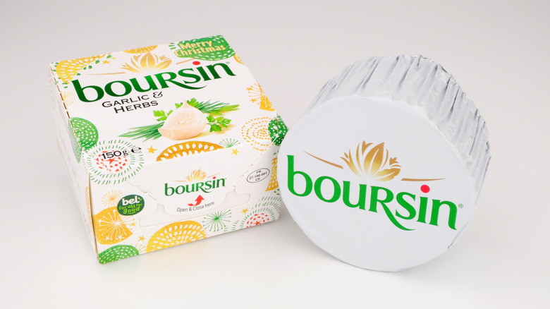 Garlic and herb Boursin cheese in packaging on white background