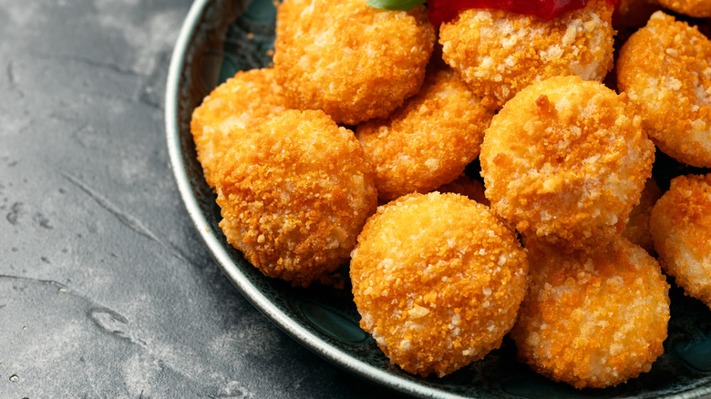Pile of crispy breadcrumb-coated cheese balls on plate