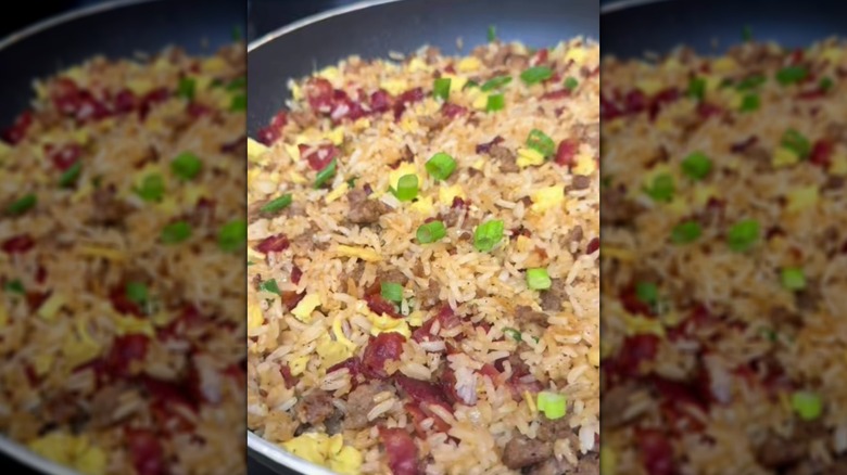 Breakfast fried rice with sausage, bacon, and egg in frying pan