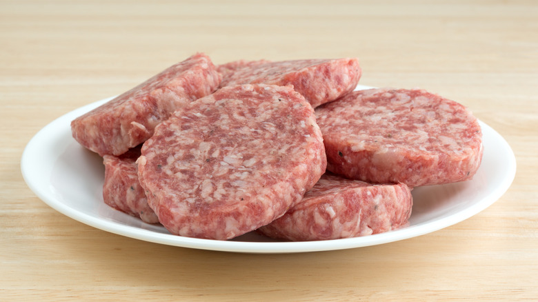 Raw breakfast sausage patties on white plate