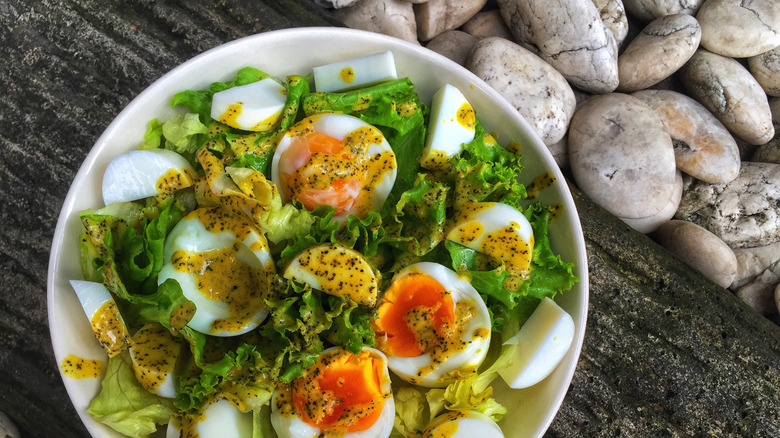 Passion fruit dressing over salad with poached egg