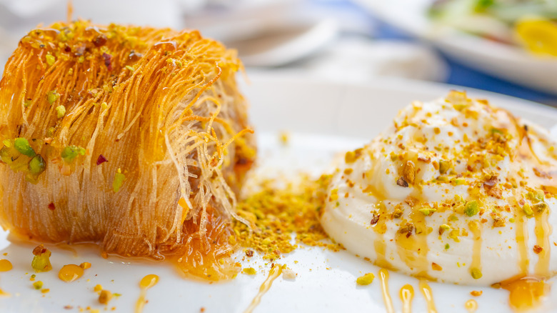 A dessert of katayif with syrup, pistachios, and cream