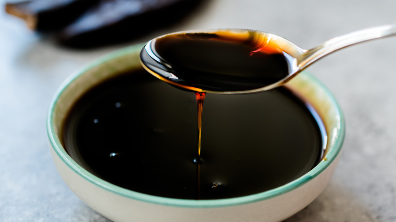 Dark molasses poured from a spoon into a bowl