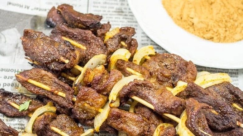 Suya skewers atop a newspaper