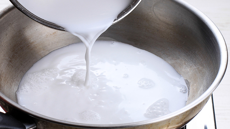 Pouring coconut milk into metal bowl
