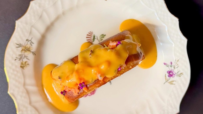 Lobster roll with uni bearnaise on white floral plate
