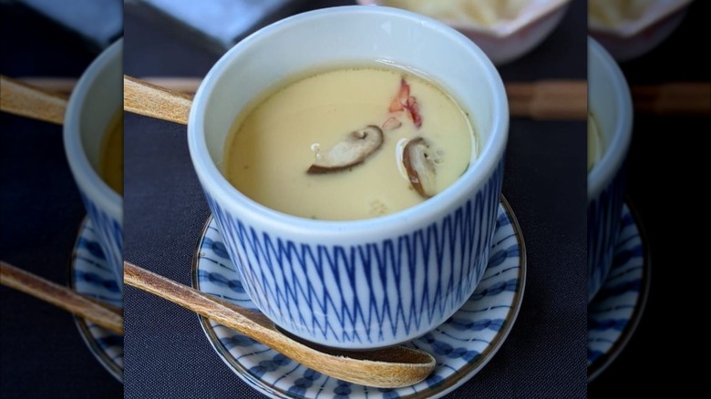 Cup of creamy custard in blue and white porcelain with wooden spoon