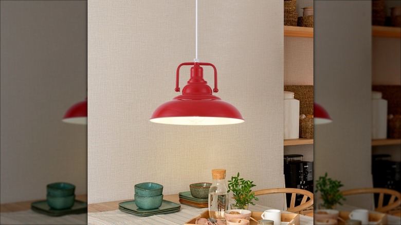 A rustic, red metal lamp hanging over a table