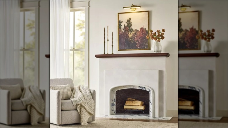 A brass gallery light illuminating a painting hanging over a fireplace
