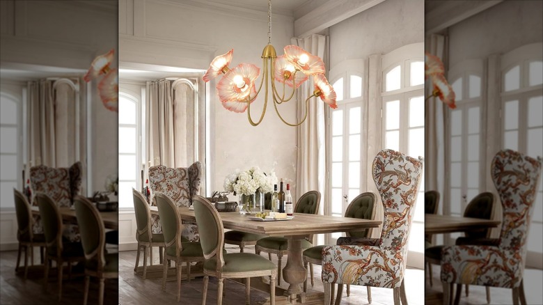 A glass pink flower chandelier hanging over a dining room table