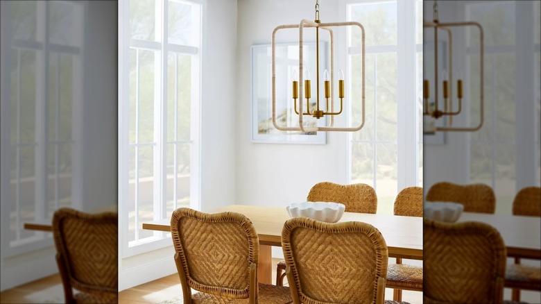A rattan and brass candle-style chandelier hanging over a table